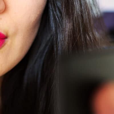 woman applies hot pink lipstick