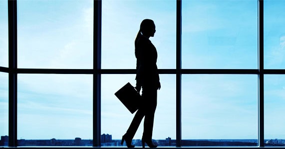 professional woman wears stylish suit; she is silhouette against a window 
