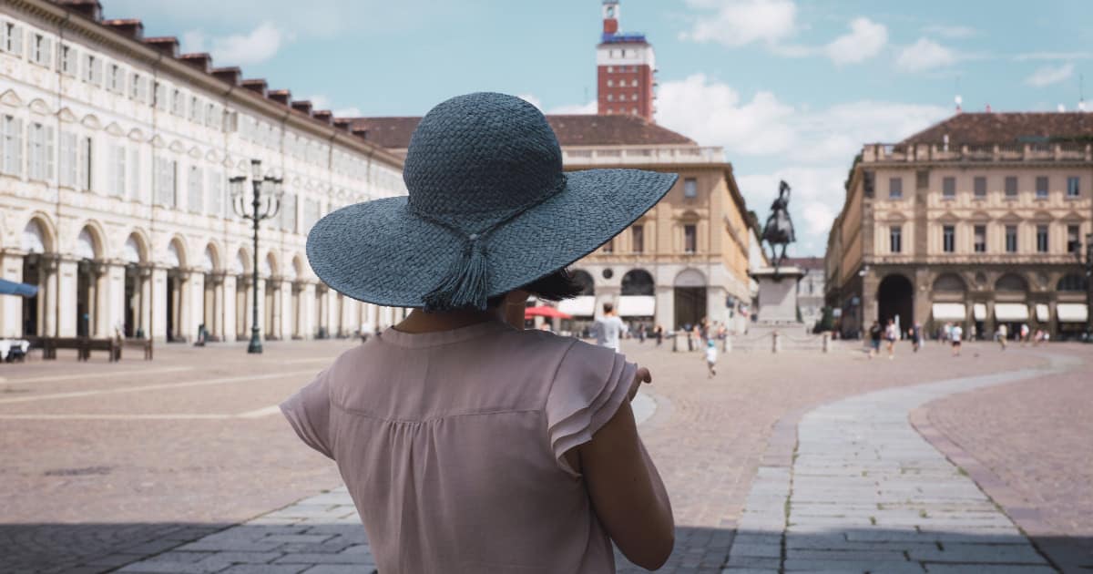 young professional woman in sunhat and pink dress looking at Roman courtyard