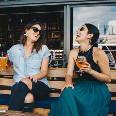 two women laughing at a bar