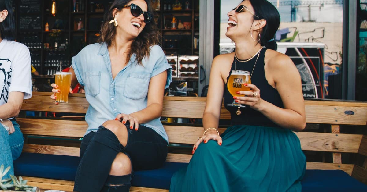 two women laughing at a bar