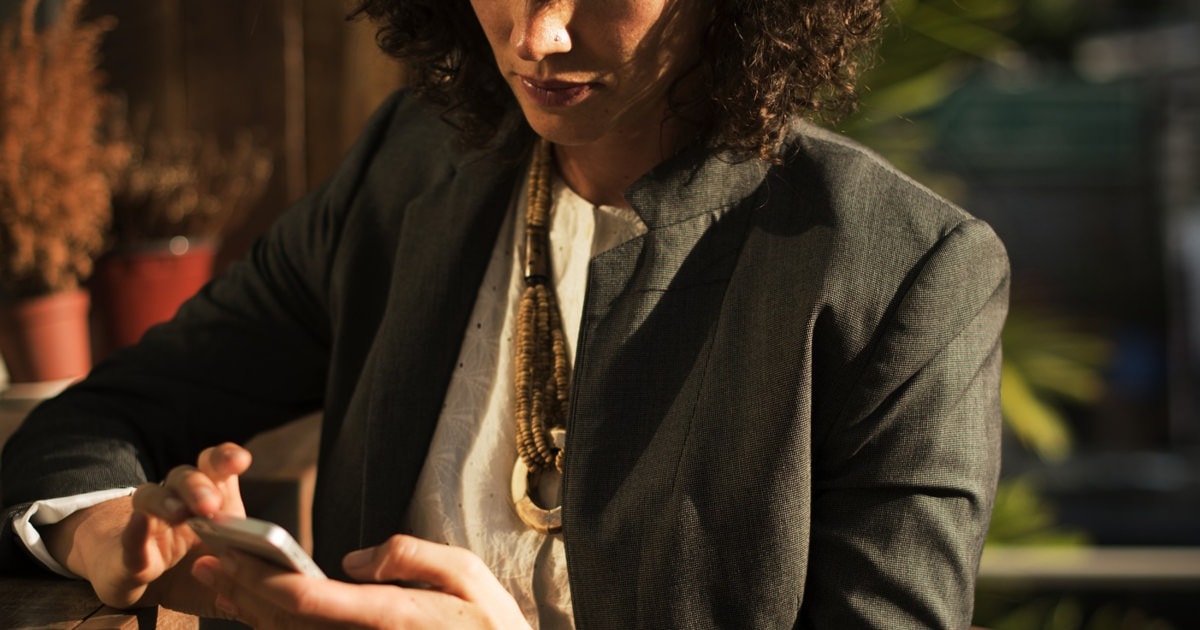 tall woman in a suit with curly hair looking at her phone
