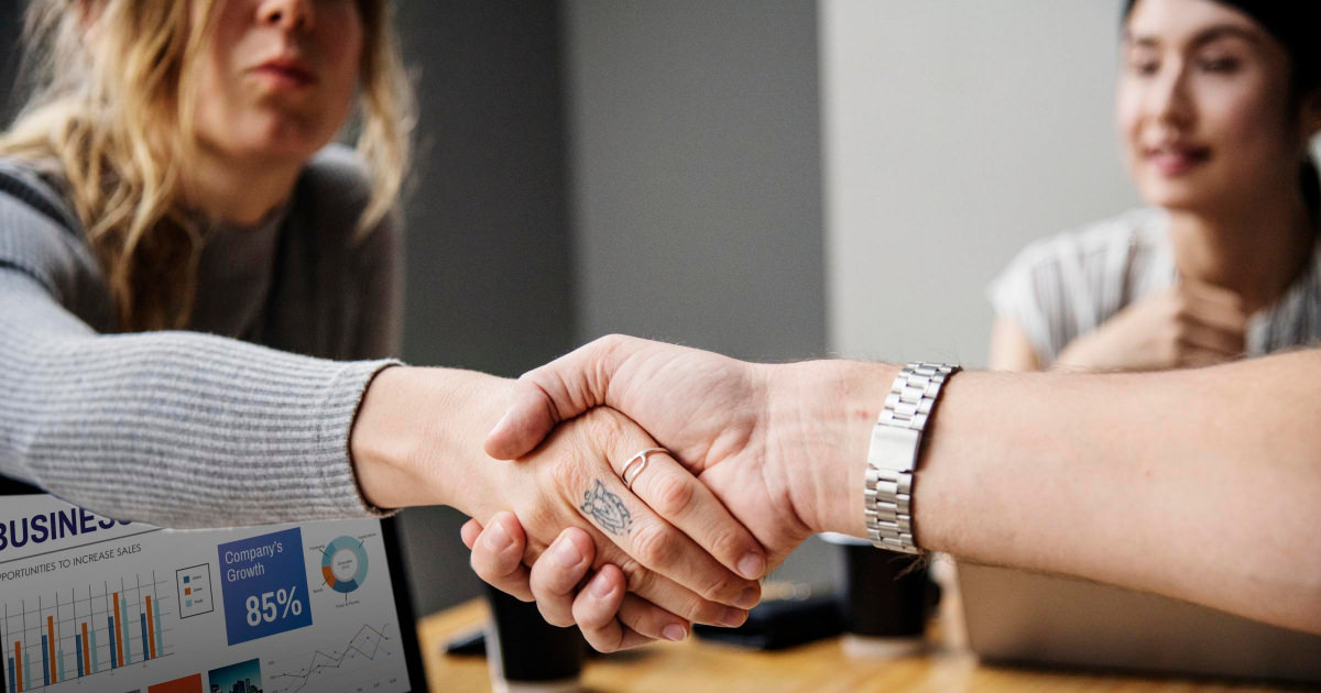 young women shake hands at a table at a female-focused workspace