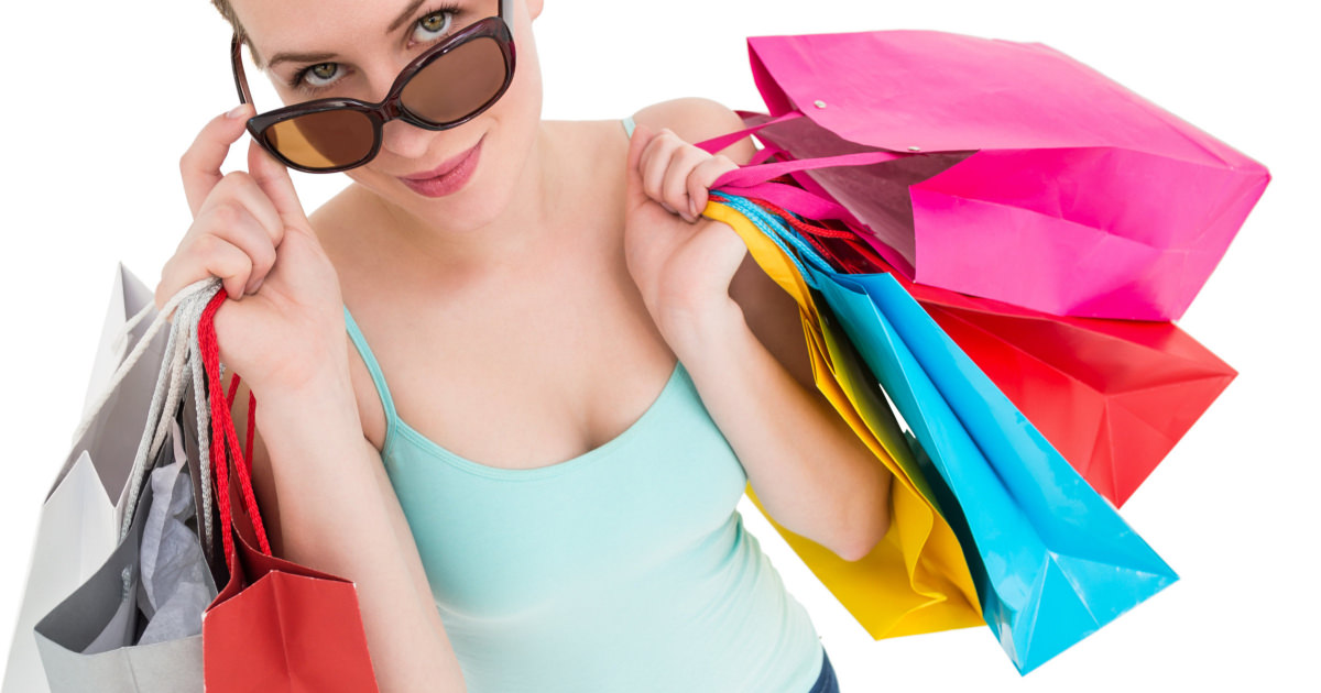 stock photo of a white woman holding 7 colorful shopping bags and sunglasses