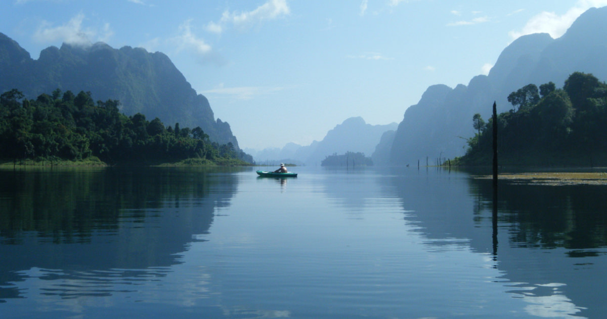 stock photo of a person kayaking on a serene mountainside lake