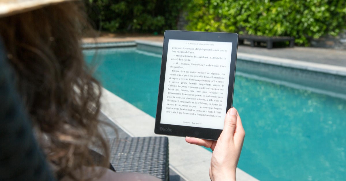 woman holding a kindle by the pool