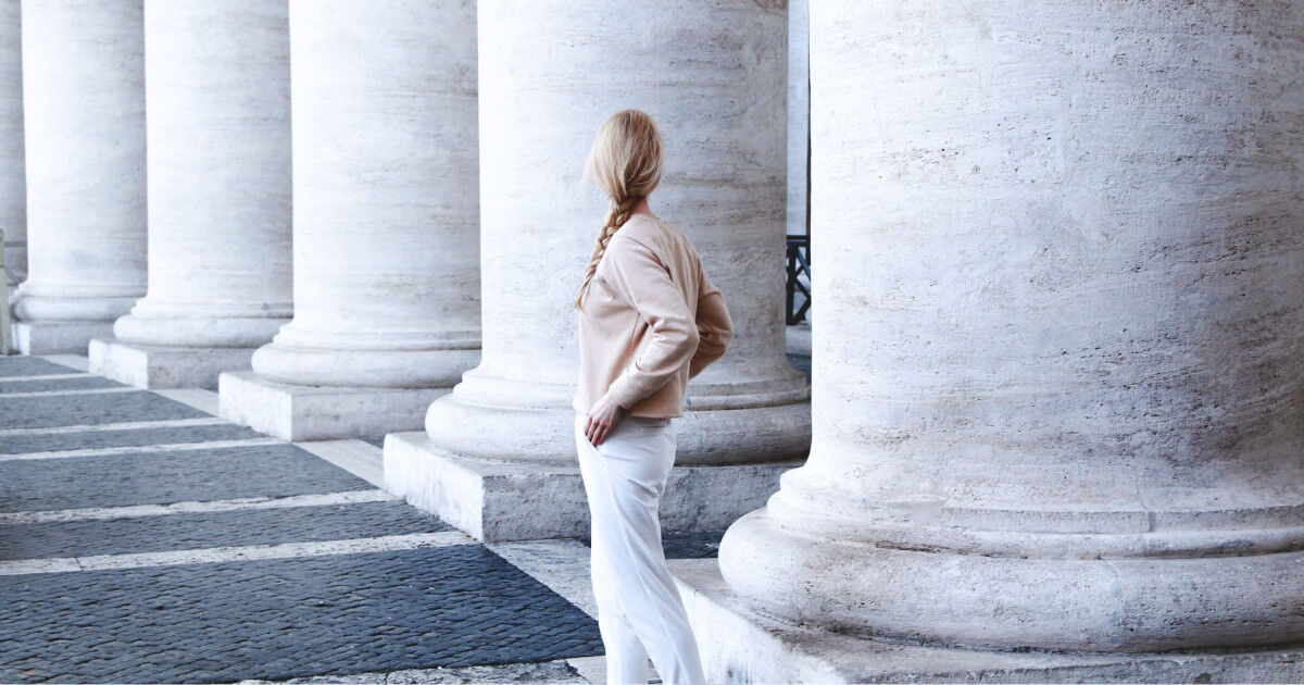 young professional woman walking by herself among large columns