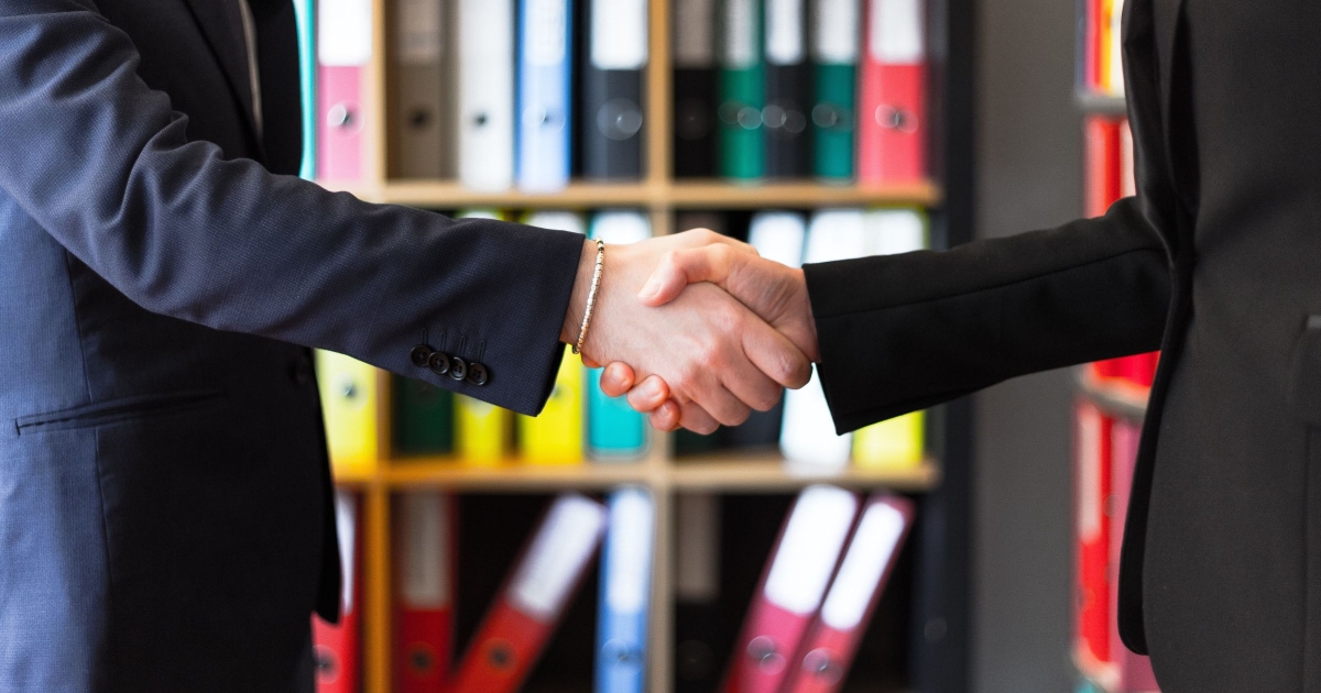 young professional woman in suit and man in suit, shaking hands 