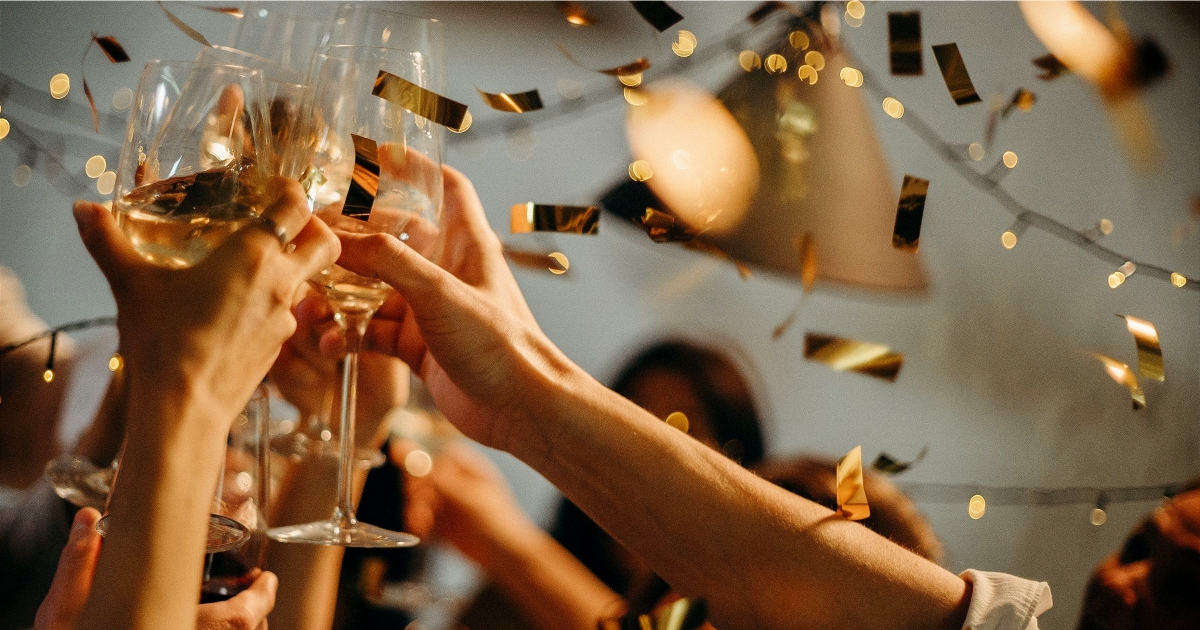 image of people toasting champagne while gold confetti comes down