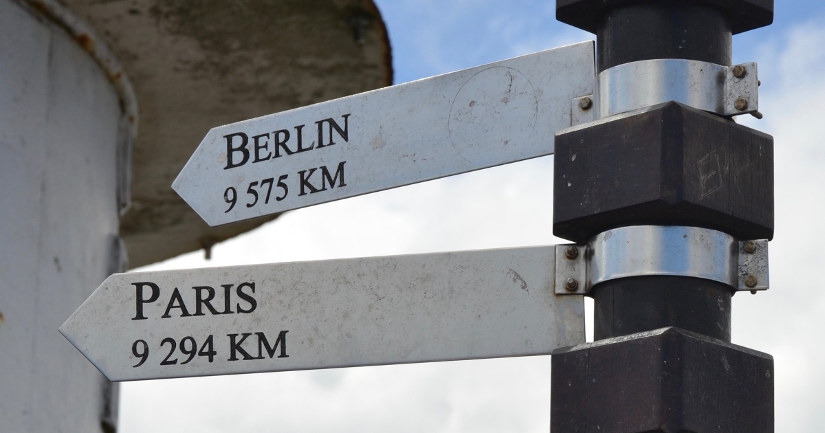 street signs pointing towards Berlin and Paris and how many KM away