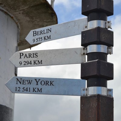travel wayfinders reading Berlin, Paris, and New York (with distance in KM)