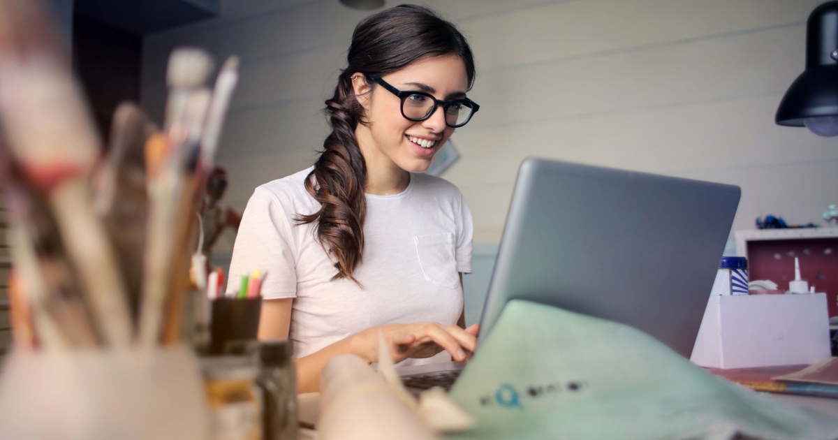 young professional woman working at a laptop, wearing a white t-shirt