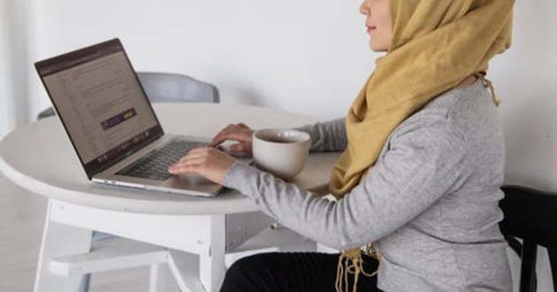 woman working on laptop from her kitchen table