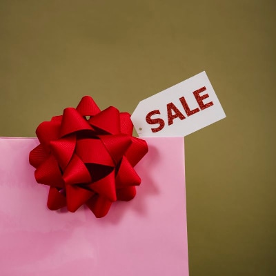 Wrapped in pink paper with a red bow, the box has a label that says SALE.