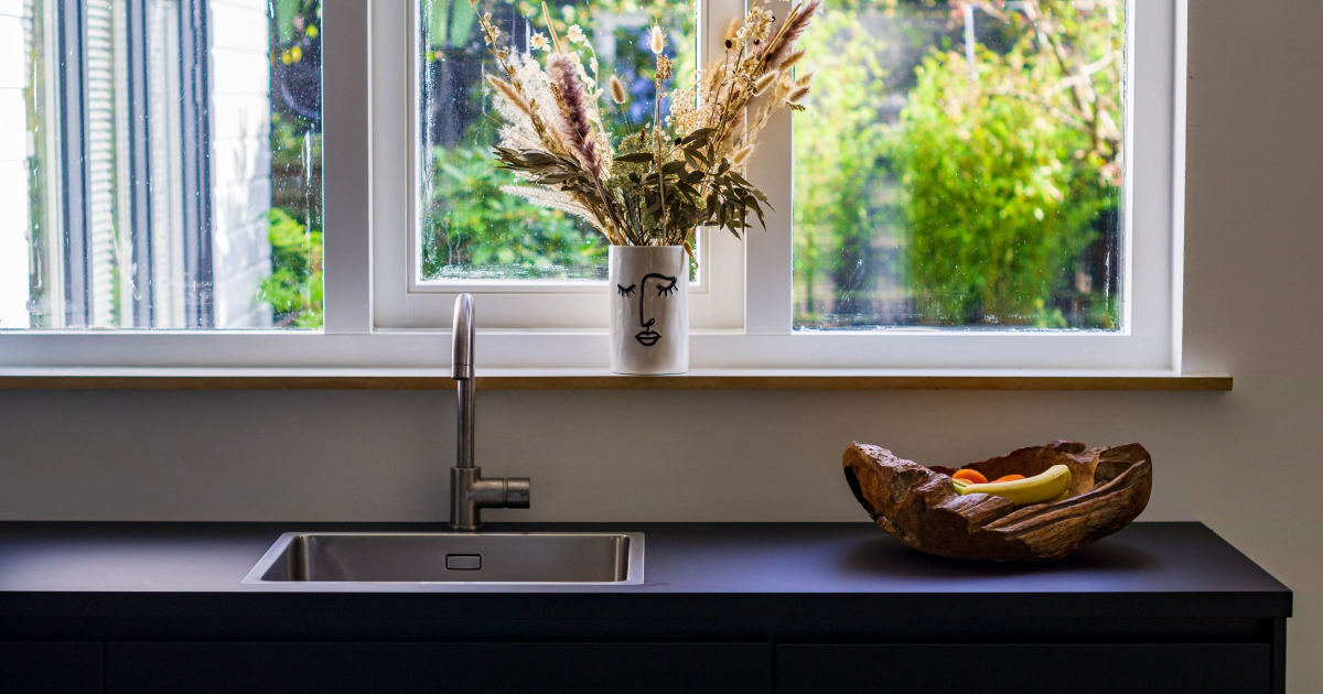 dark black sink in front of window with silly mug above sink