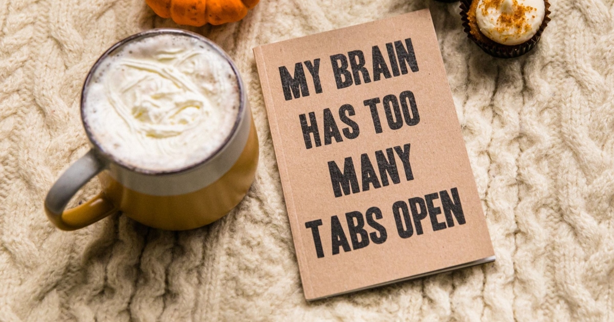 notebook and hot cocoa on knit blanket; notebook says "My Brain Has Too Many Tabs Open" 