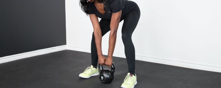 woman wearing yellow sneakers, lifting a kettlebell