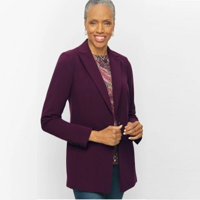 Older Black woman with short gray hair wearing a purple blazer and blue jeans