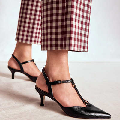 womn wears black t-strap pumps with low heel
