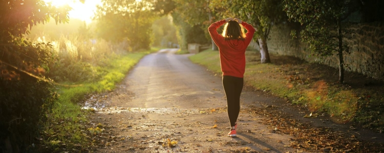 woman walking along sunny path with her arms on top of her head looking a bit overwhelmed