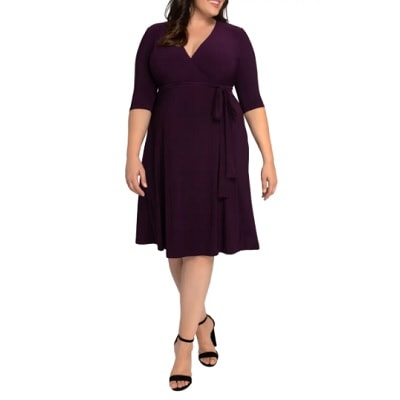 A white woman with long brown hair (face cropped out) wearing a purple wrap dress and black sandals 