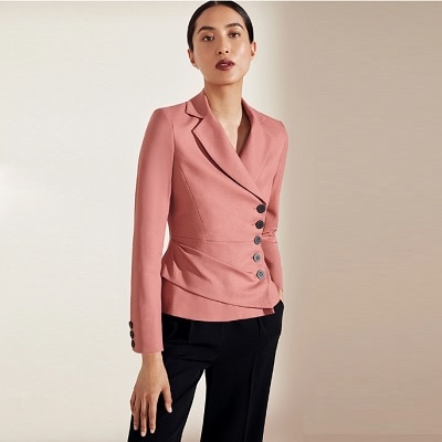 An Asian woman with a pink blazer and black pants (legs cropped out)