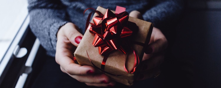 woman holding small wrapped present with red ribbon 