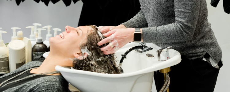 woman getting her hair washed in a salon sink by another woman