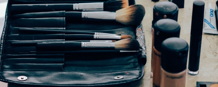 makeup brushes and makeup bottles spread out on a bathroom counter