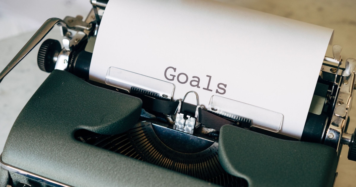 A typewriter on a table with the word "Goals" typed on a white paper