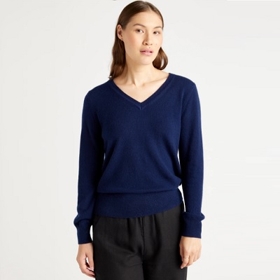 A woman in a blue cashmere sweater and black pants (legs cropped out)