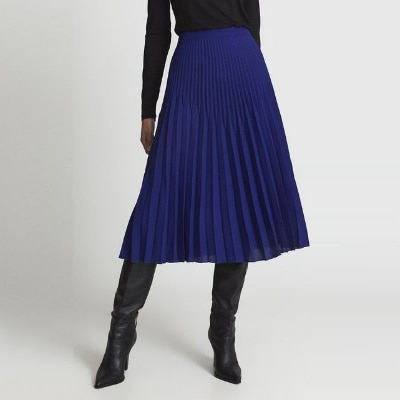 A woman wearing a black shirt, dark blue pleated skirt, and knee-high black boots (torso cropped out)
