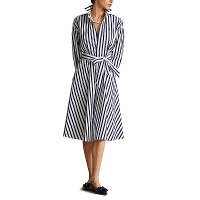 A woman (head mostly cropped out) wearing a navy-and-white striped shirtdress and navy slingbacks 