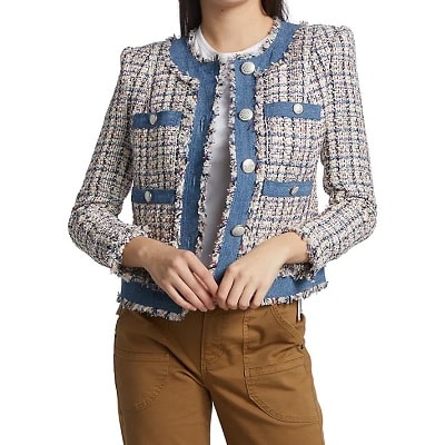 A woman (head and legs cropped out) wearing a multicolored tweed jacket with blue trim with brown pants