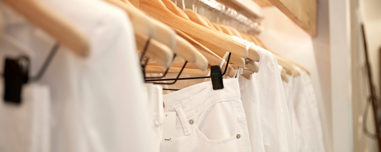 white pants, blouses, and blazers hang on a store rack