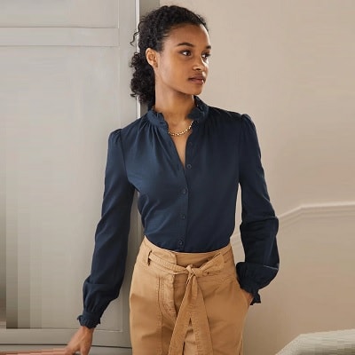 woman in navy shirt with a ruffle broderie collar detail
