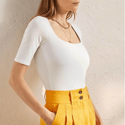 opaque white tee with scoopneck and elbow-length sleeves; styled with yellow high-waisted pleated pants