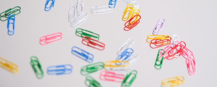 colorful paperclips scattered on a white surface
