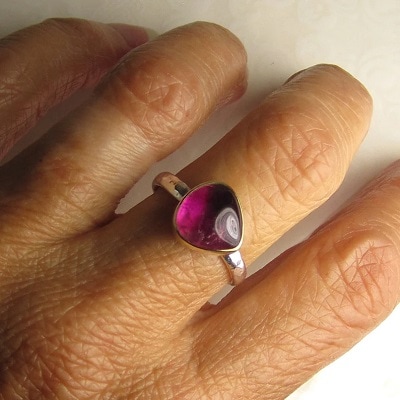 woman's hand wearing a silver ring with a large circularish pink stone