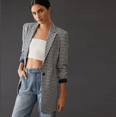 woman wears black gingham blazer with sleeves rolled up, white crop top and blue jeans