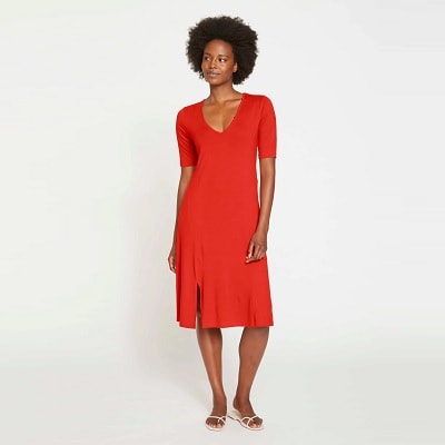 A woman with an afro wearing a red midi-length dress and sandals