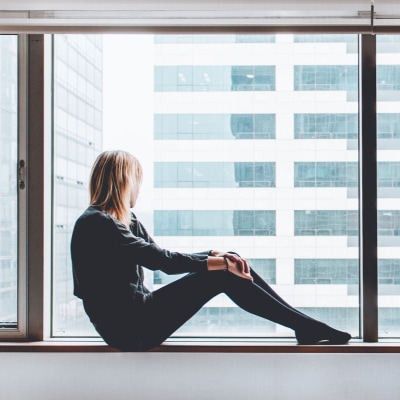 young professional woman who is considering divorce looks out a window on a gray, bleary day