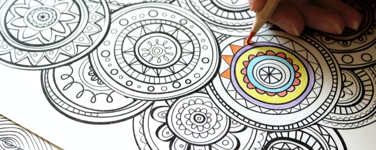 person colors in a mandala in a coloring book