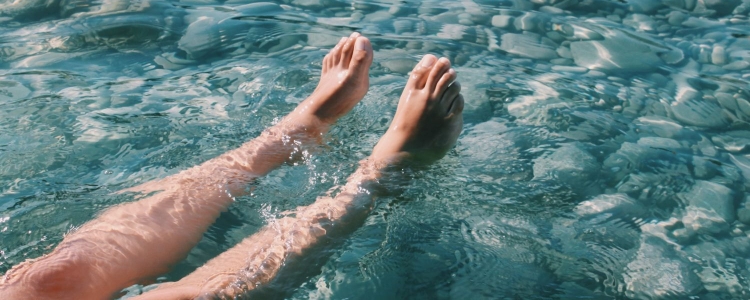 a woman's bare legs float in the water; they are not noticeably hairy. 