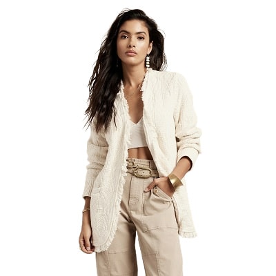 model wears a white knit blazer with fringe details and a textured knit, along with a white crop top and beige cargo pants.