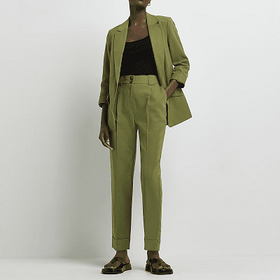 model wears a puce green suit; the pants are pleated, cropped, and have pressed cuffs