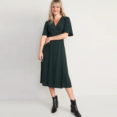 A woman wearing a dark green wrap dress and black boots