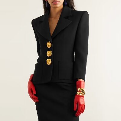 black blazer with large gold buttons; she wears red leather gloves with the look