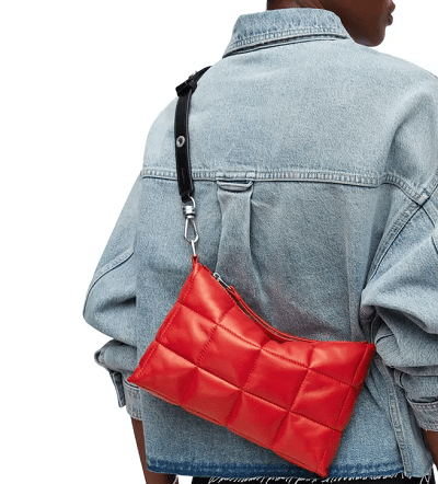 bright red bag with quilting details; it is shown worn by a woman wearing a denim jacket