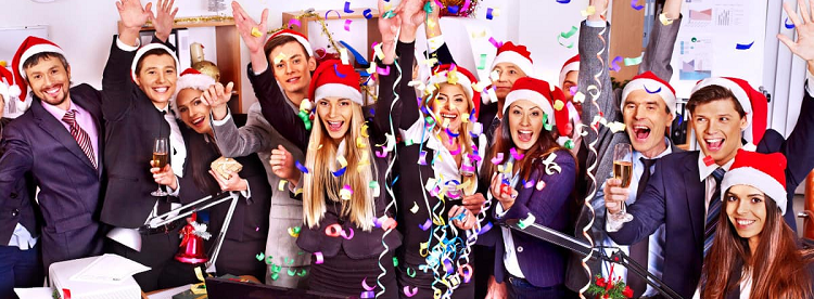 crowd of businesswomen and businessmen in suits and Santa hats celebrating with champagne and confetti